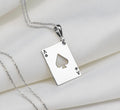 Silver pendant necklace featuring an Ace of Spades design with a four of Hearts and Ace of Diamonds motif. The pendant has a polished surface finish and is attached to a silver chain.