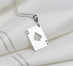 Silver pendant necklace featuring an Ace of Spades design with a four of Hearts and Ace of Diamonds motif. The pendant has a polished surface finish and is attached to a silver chain.