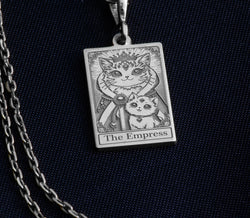 Silver pendant featuring a detailed design of a cat surrounded by ornate borders and the text "The Empress". The pendant has a polished surface finish and is shown from a slight angle against a dark background.