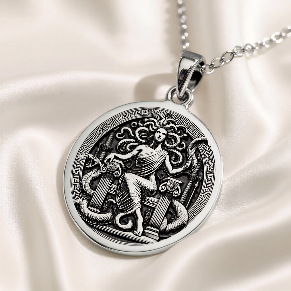 Silver pendant featuring a detailed Medusa Gorgon motif with an ancient mythological design. The pendant has a smooth, polished surface finish and is shown from a slight angle. It is presented as a standalone item.