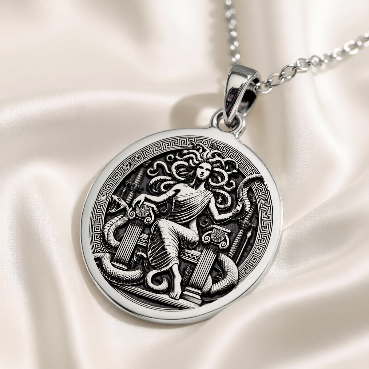 Silver pendant featuring a detailed Medusa Gorgon motif with an ancient mythological design. The pendant has a smooth, polished surface finish and is shown from a slight angle. It is presented as a standalone item.