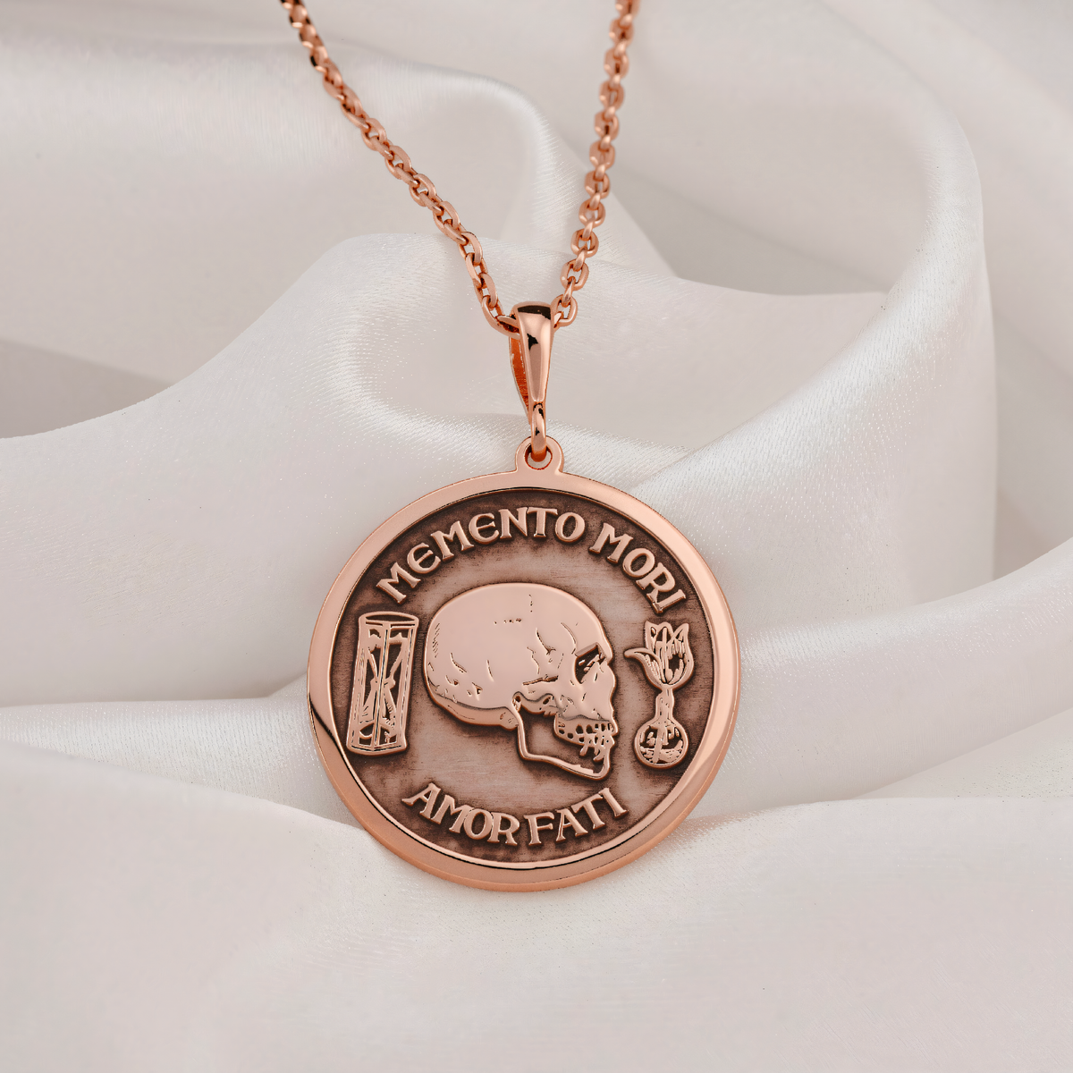 Memento Mori Skull Necklace in rose gold plated showing front view with engraved skull, hourglass, tulip and Latin text.