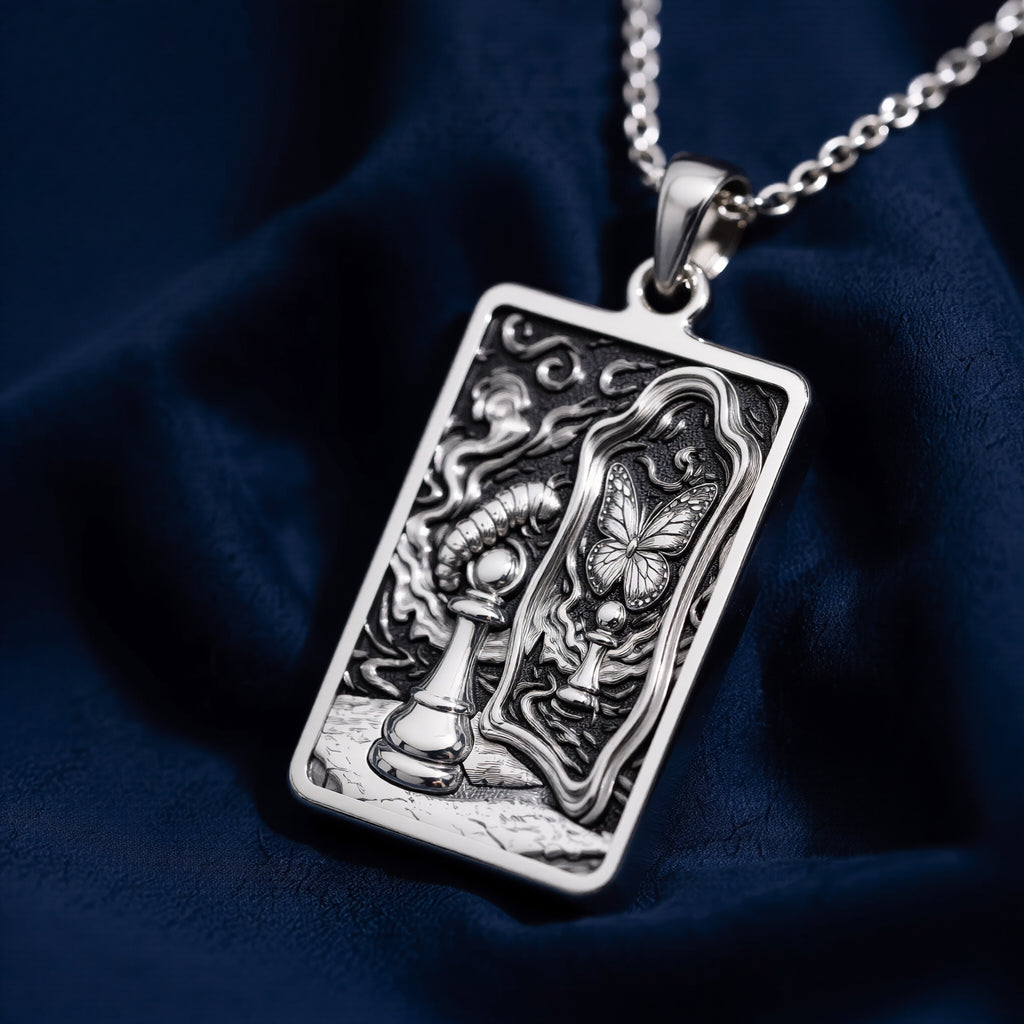 Silver toned rectangular pendant with detailed line art design. This necklace is displayed on black fabric alongside several faceted gemstones. - View 4