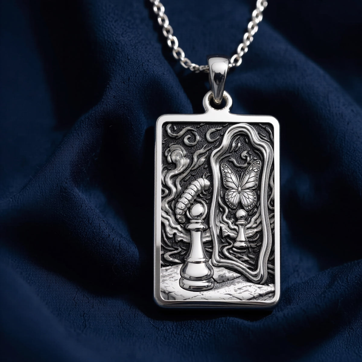Silver toned rectangular pendant with detailed line art design. This necklace is displayed on black fabric alongside several faceted gemstones. - View 5