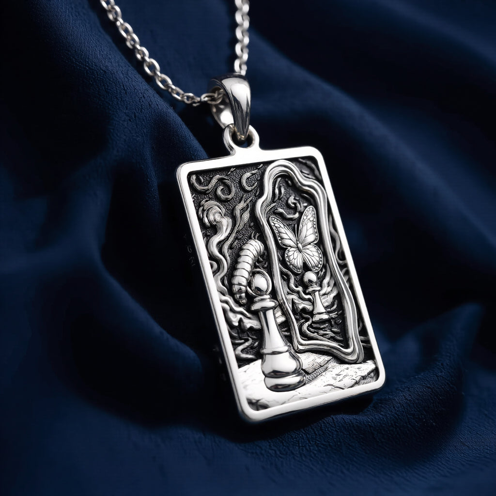 Silver toned rectangular pendant with detailed line art design. This necklace is displayed on black fabric alongside several faceted gemstones. - View 6