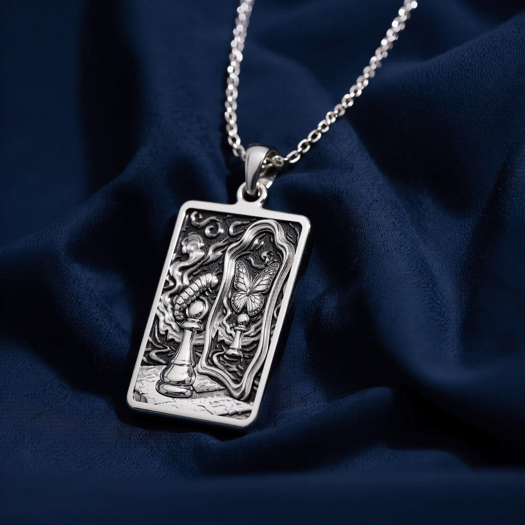 Silver toned rectangular pendant with detailed line art design. This necklace is displayed on black fabric alongside several faceted gemstones. - View 7