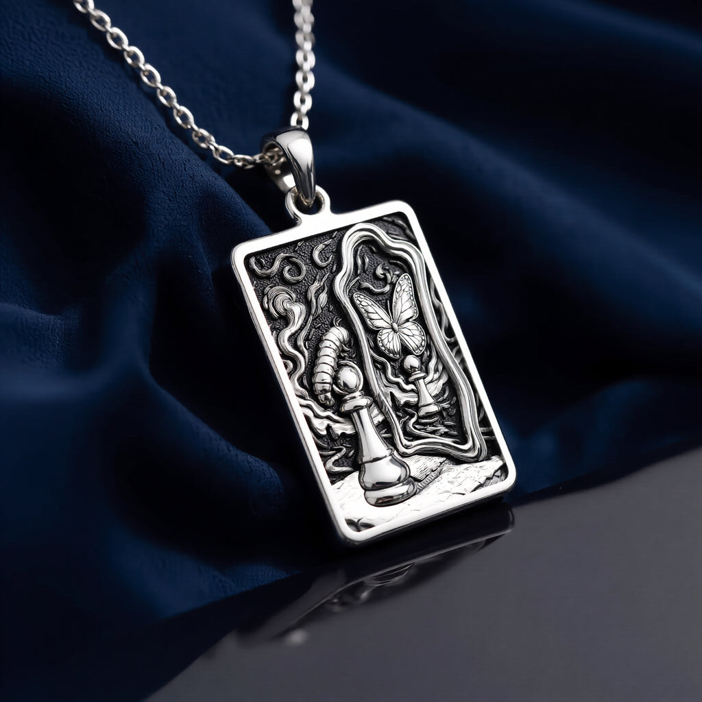 Silver toned rectangular pendant with detailed line art design. This necklace is displayed on black fabric alongside several faceted gemstones. - View 8