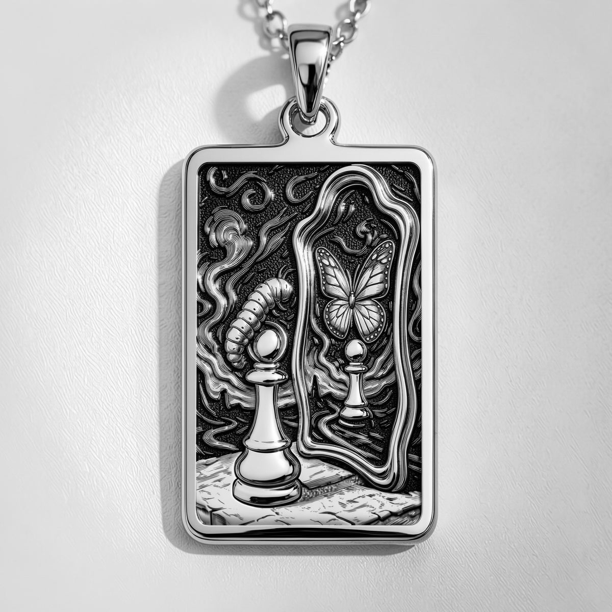 Silver toned rectangular pendant with detailed line art design. This necklace is displayed on black fabric alongside several faceted gemstones.