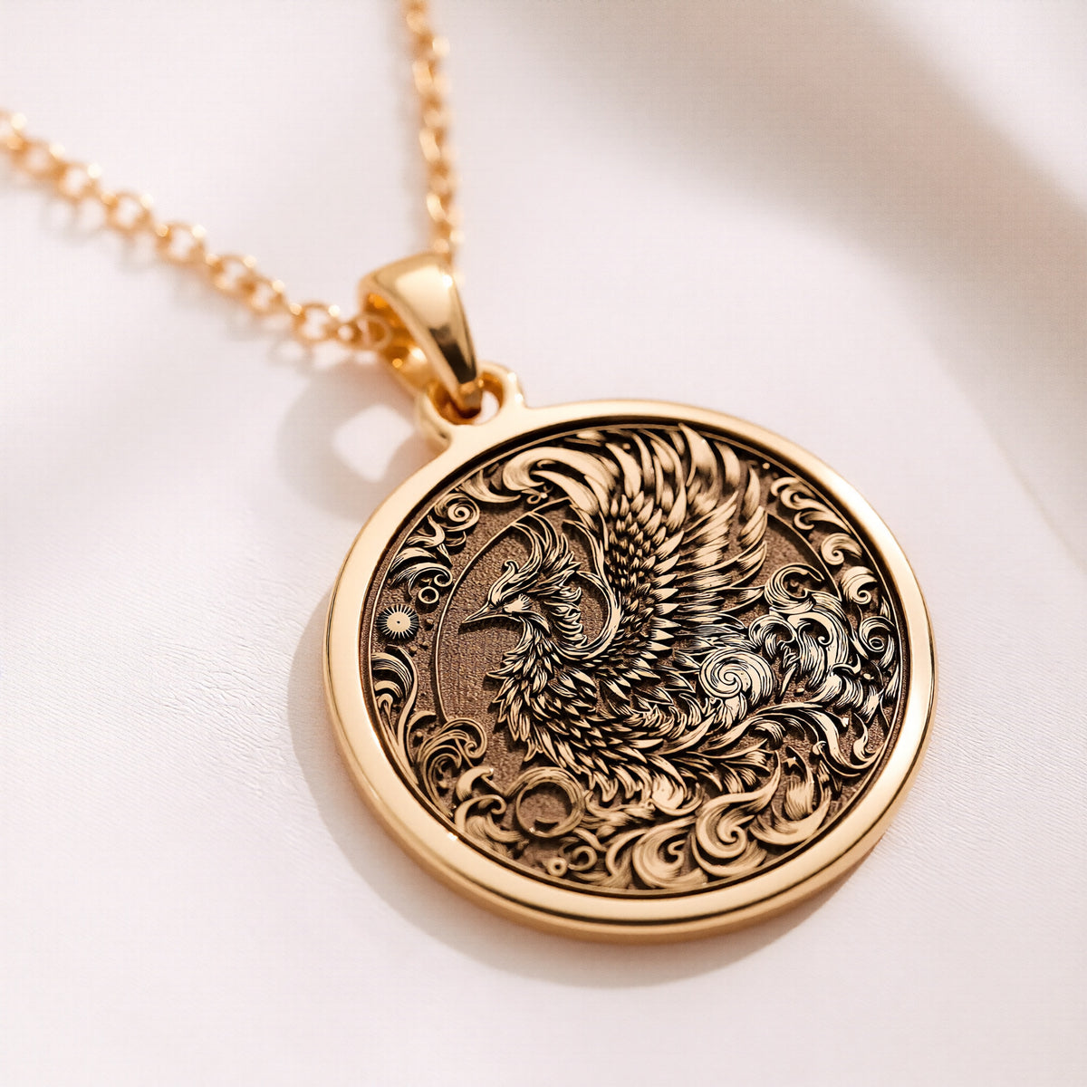 Phoenix Medallion pendant in 14K gold showing front view of engraved phoenix with swirling details and sun motif.