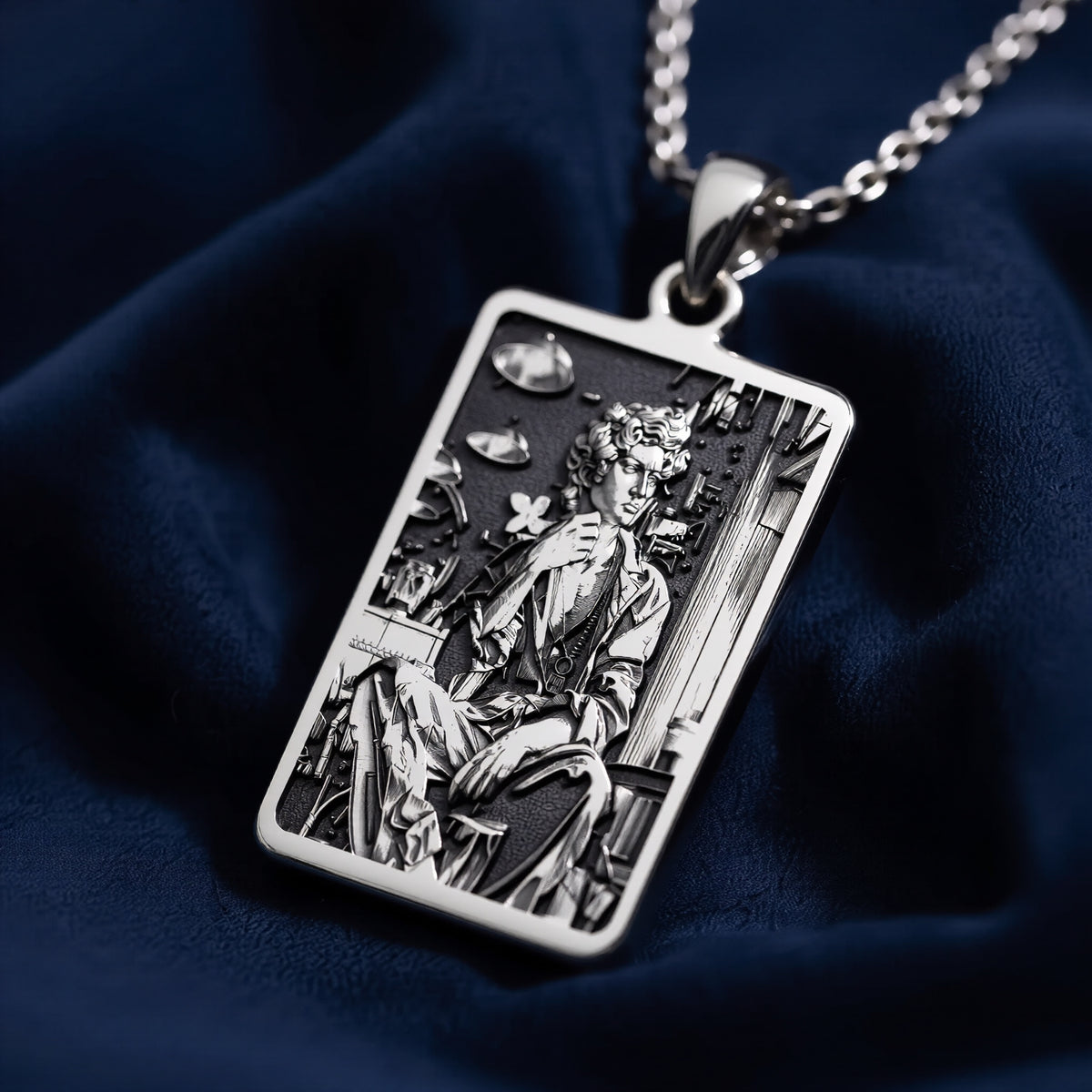 Silver rectangular pendant featuring an engraved classical design. This piece is suspended by a silver-toned chain and presented on a dark backdrop, emphasizing the detailed texture of the metal. - View 4