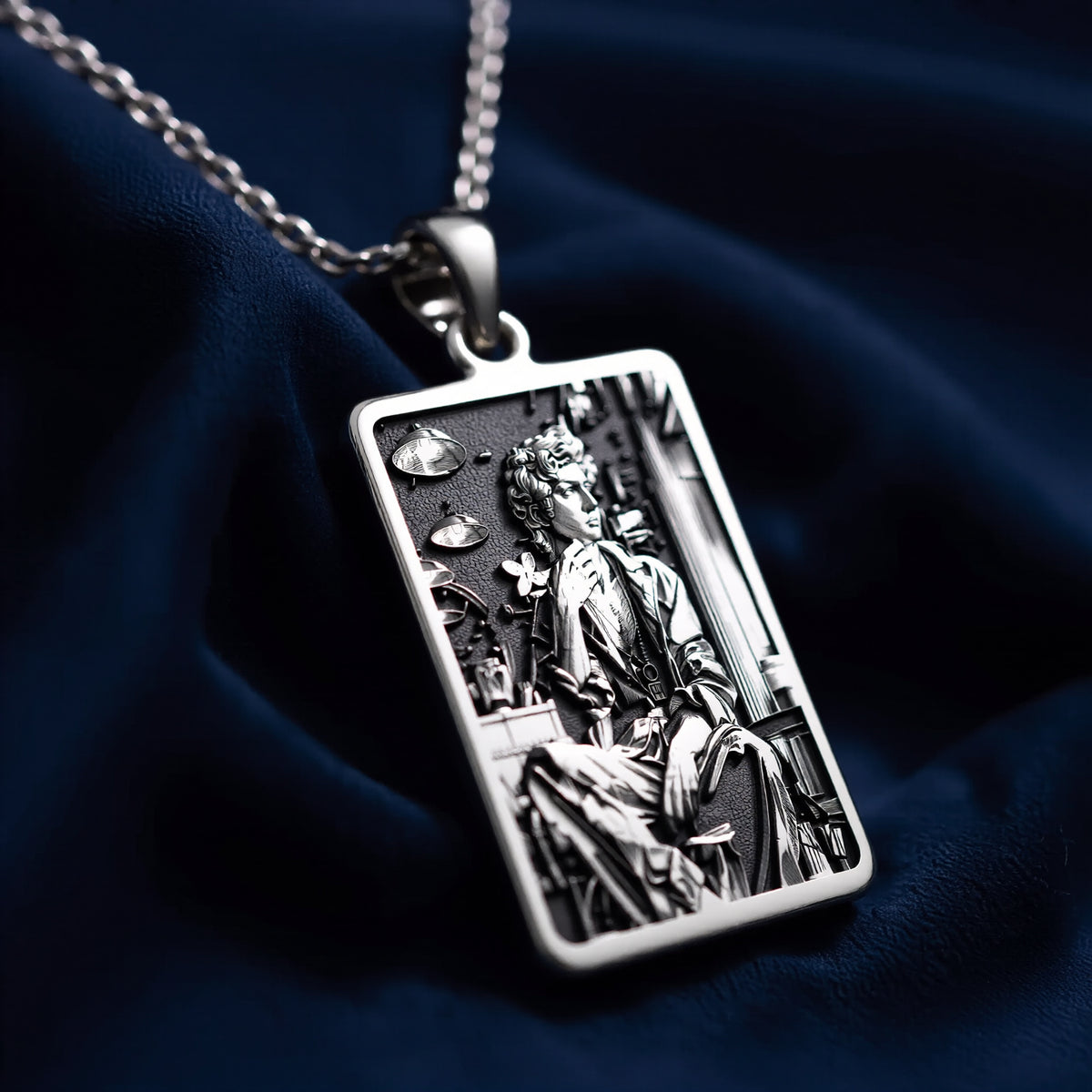 Silver rectangular pendant featuring an engraved classical design. This piece is suspended by a silver-toned chain and presented on a dark backdrop, emphasizing the detailed texture of the metal. - View 6