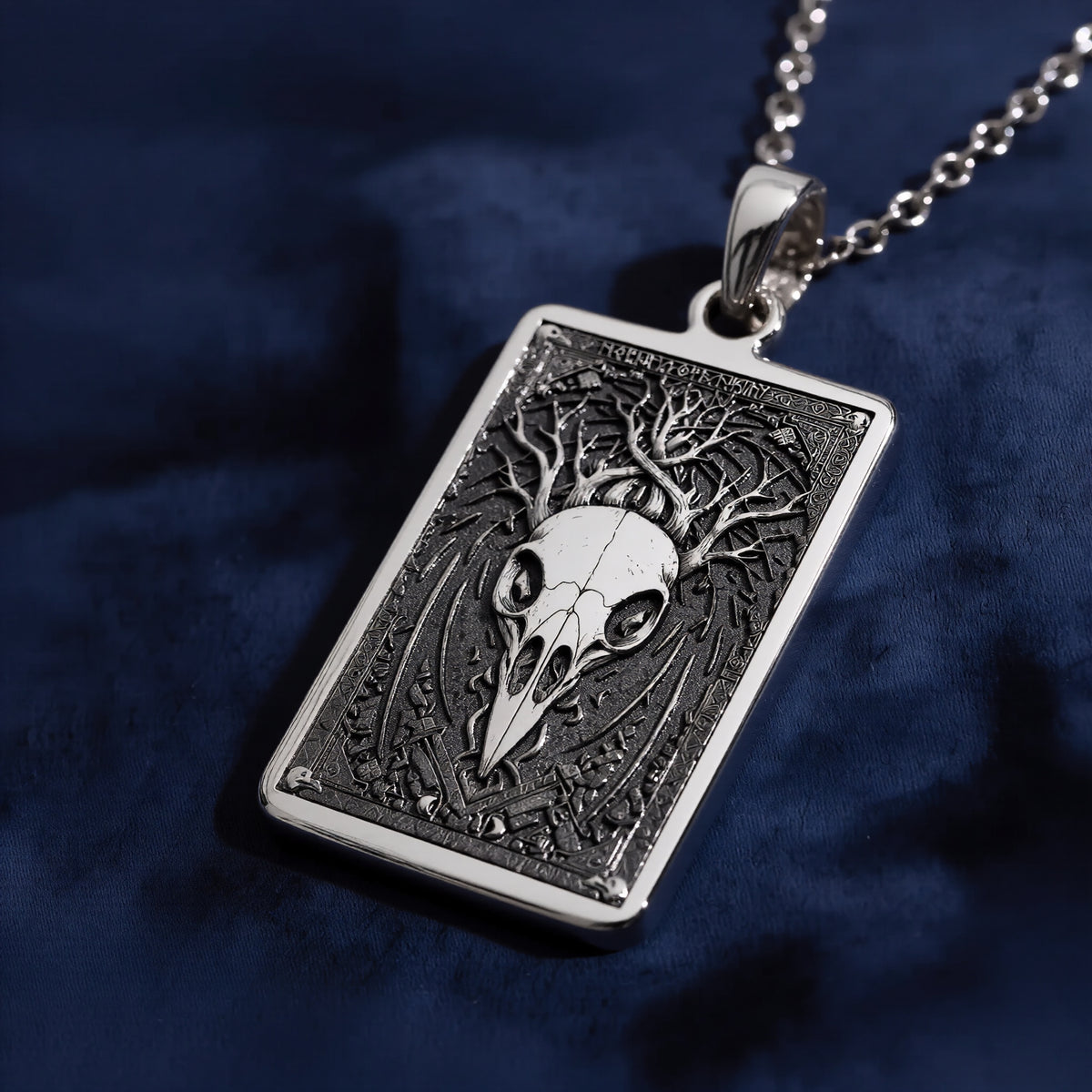 Silver pendant necklace featuring a detailed skull design with intricate framing. This silver-toned item is presented on a dark background alongside scattered faceted gemstones. - View 4