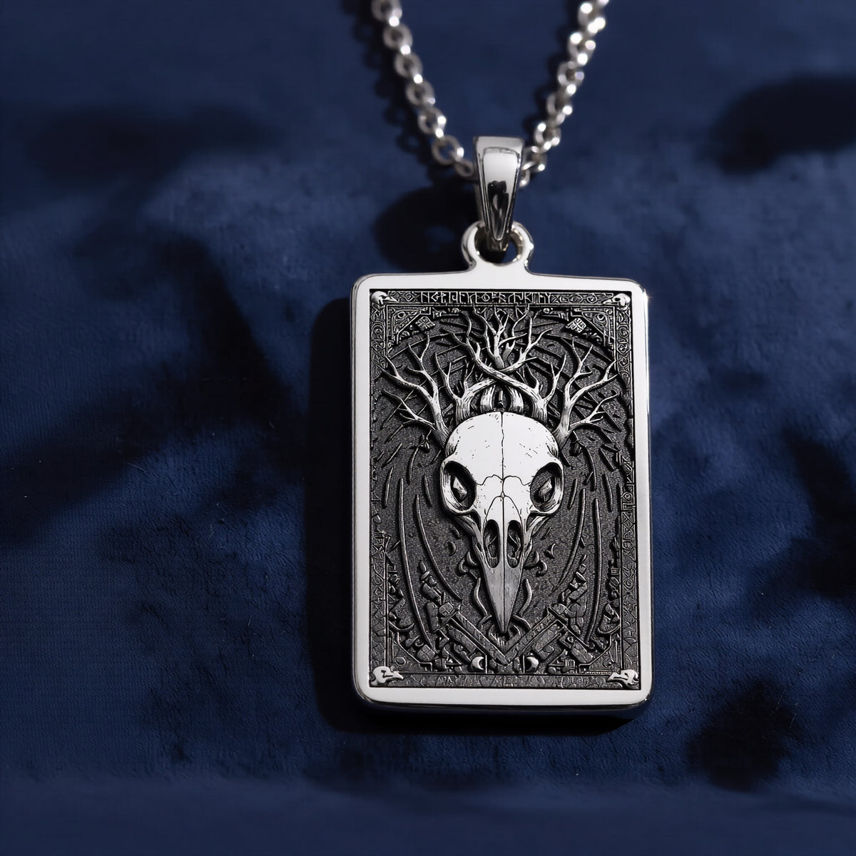 Silver pendant necklace featuring a detailed skull design with intricate framing. This silver-toned item is presented on a dark background alongside scattered faceted gemstones. - View 5