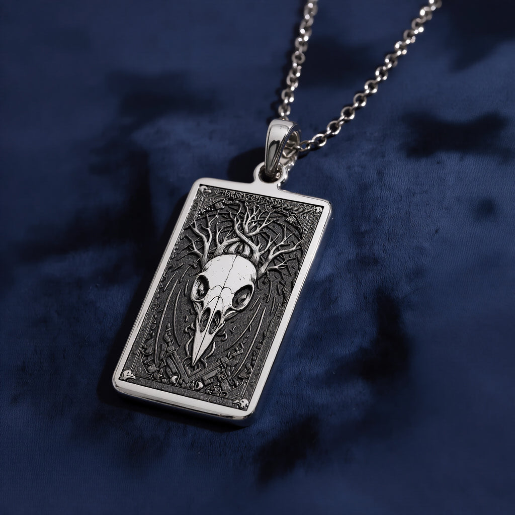 Silver pendant necklace featuring a detailed skull design with intricate framing. This silver-toned item is presented on a dark background alongside scattered faceted gemstones. - View 6