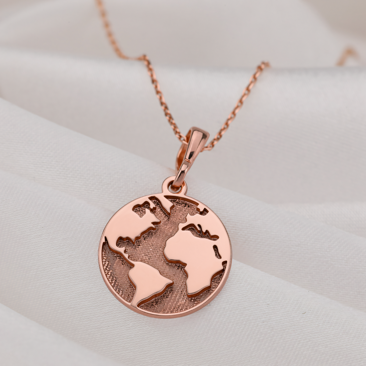 World Map Necklace in a polished rose gold finish.