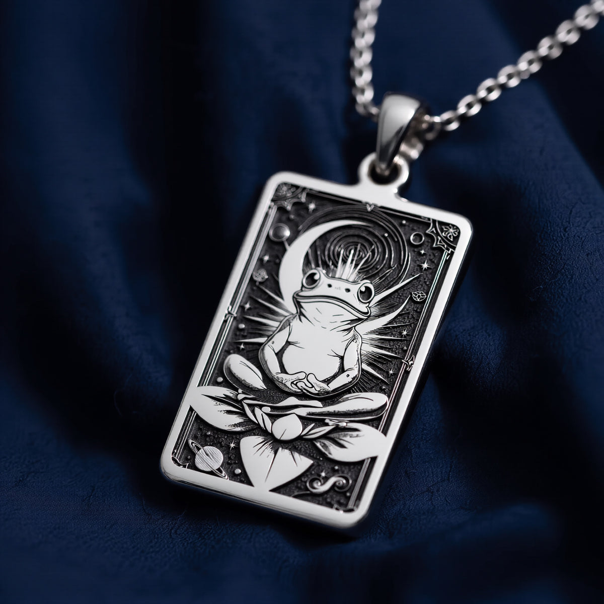 Silver rectangular pendant necklace featuring an engraved design of a frog with surrounding leaves. The metal has a bright, reflective finish and is displayed on a black background with various colored faceted stones. - View 4