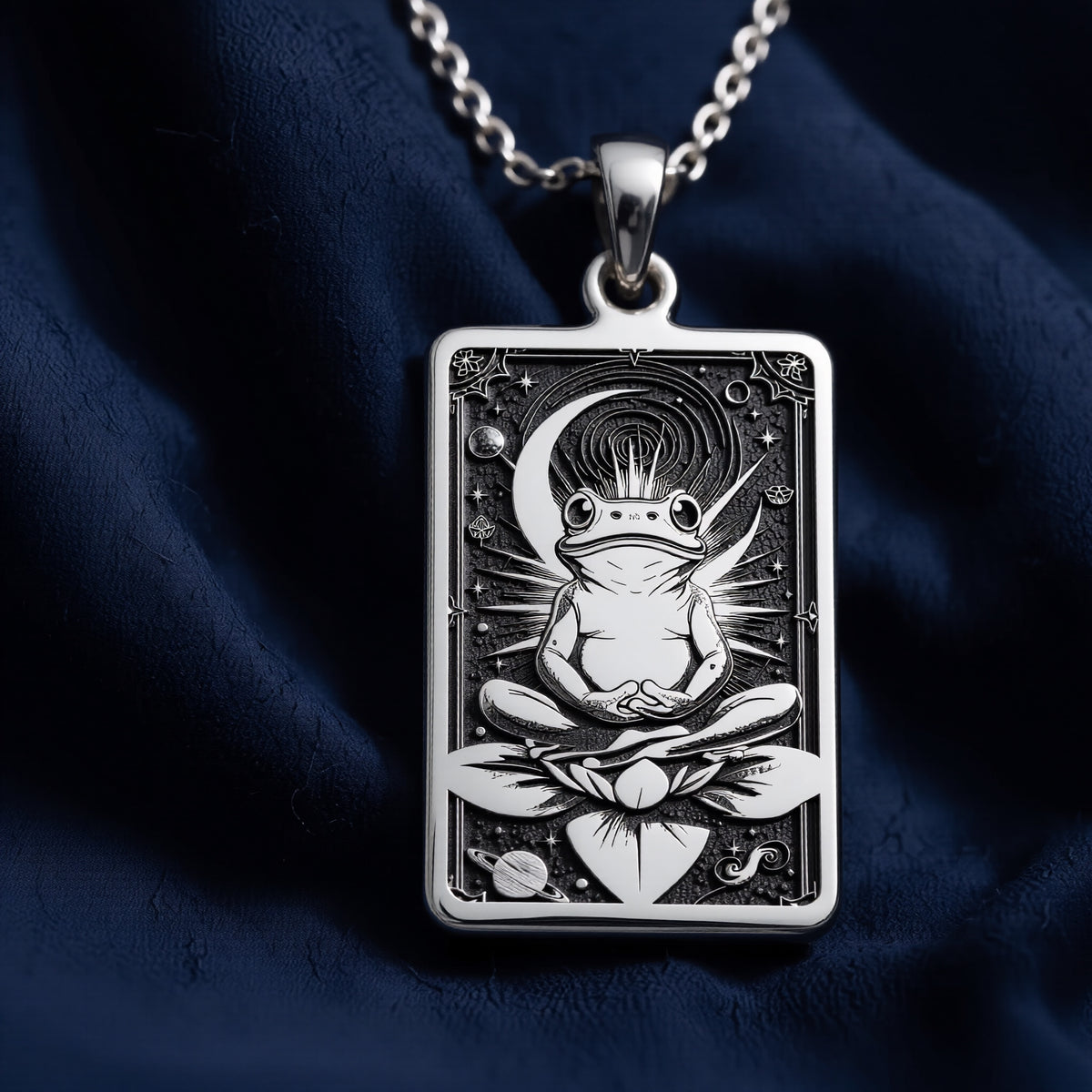 Silver rectangular pendant necklace featuring an engraved design of a frog with surrounding leaves. The metal has a bright, reflective finish and is displayed on a black background with various colored faceted stones. - View 5