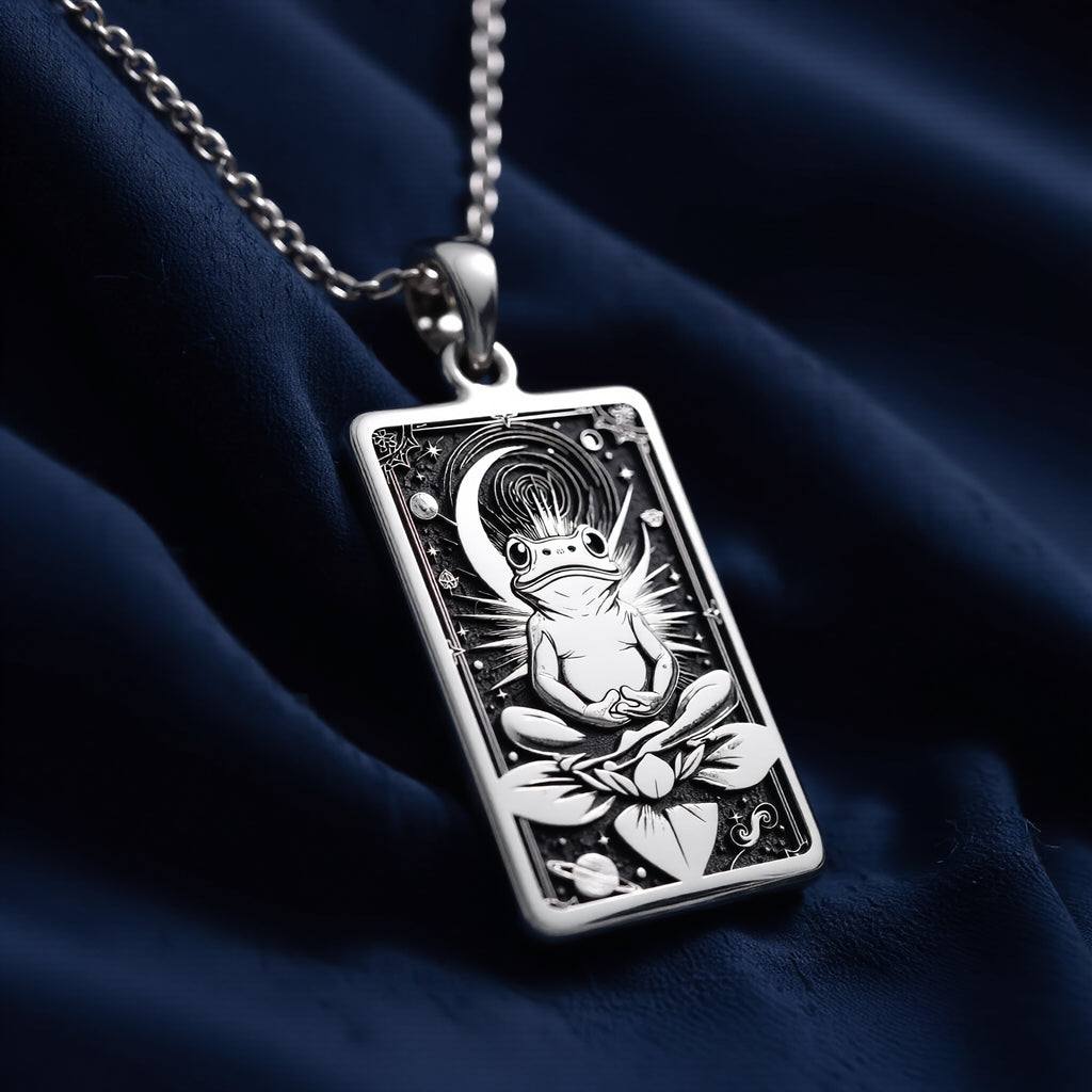 Silver rectangular pendant necklace featuring an engraved design of a frog with surrounding leaves. The metal has a bright, reflective finish and is displayed on a black background with various colored faceted stones. - View 6