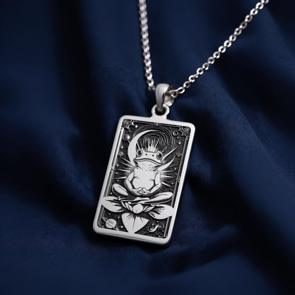 Silver rectangular pendant necklace featuring an engraved design of a frog with surrounding leaves. The metal has a bright, reflective finish and is displayed on a black background with various colored faceted stones. - View 7