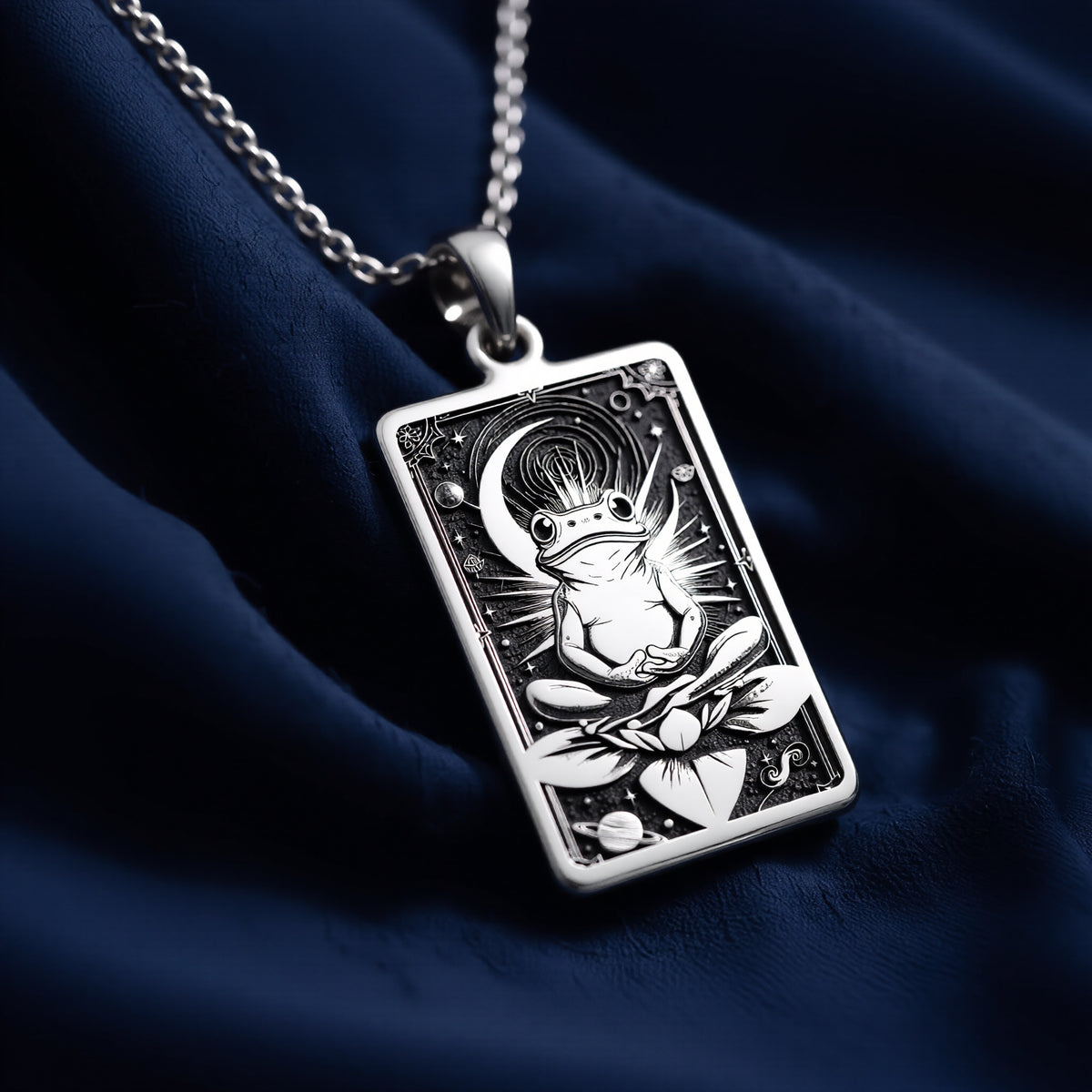Silver rectangular pendant necklace featuring an engraved design of a frog with surrounding leaves. The metal has a bright, reflective finish and is displayed on a black background with various colored faceted stones. - View 8