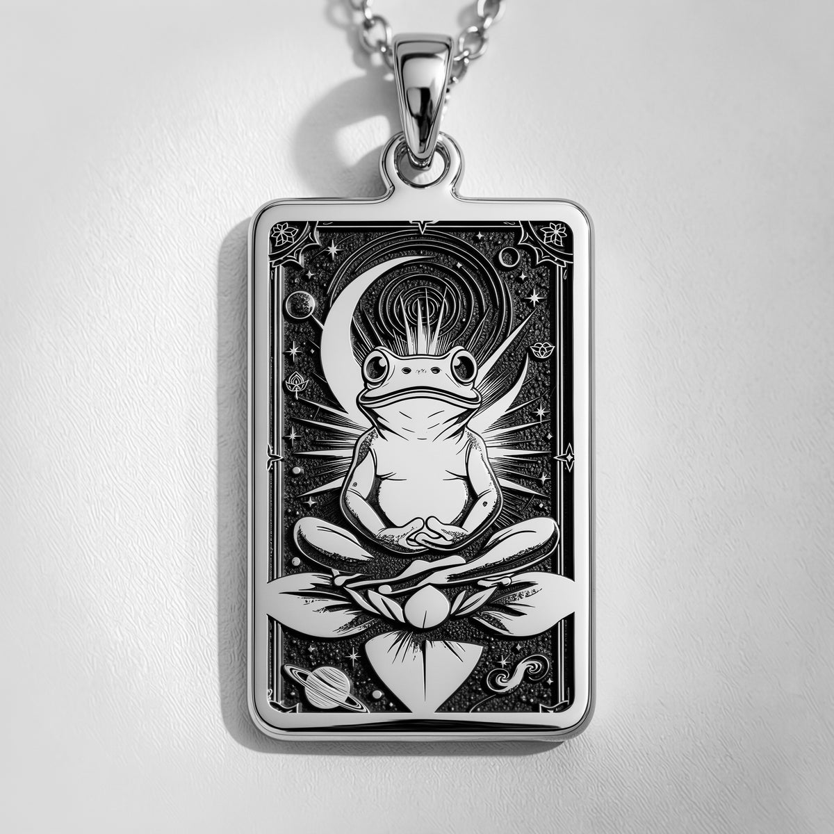 Silver rectangular pendant necklace featuring an engraved design of a frog with surrounding leaves. The metal has a bright, reflective finish and is displayed on a black background with various colored faceted stones.